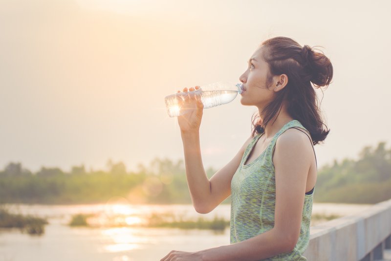 Sonnenuntergang: Eine Frau erfrischt sich mit natürlichem Mineralwasser.