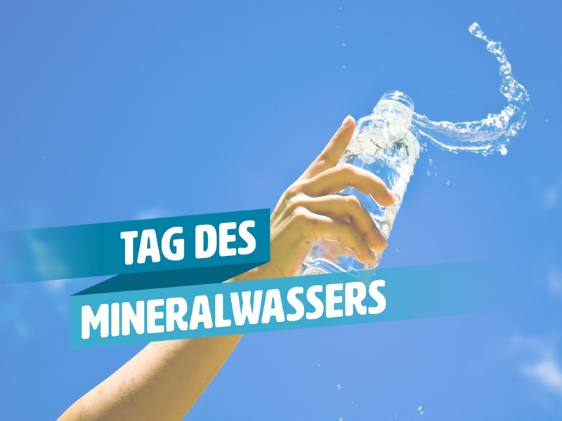 Eine Hand vor blauem Himmel hält eine Flasche Mineralwasser in die Höhe.